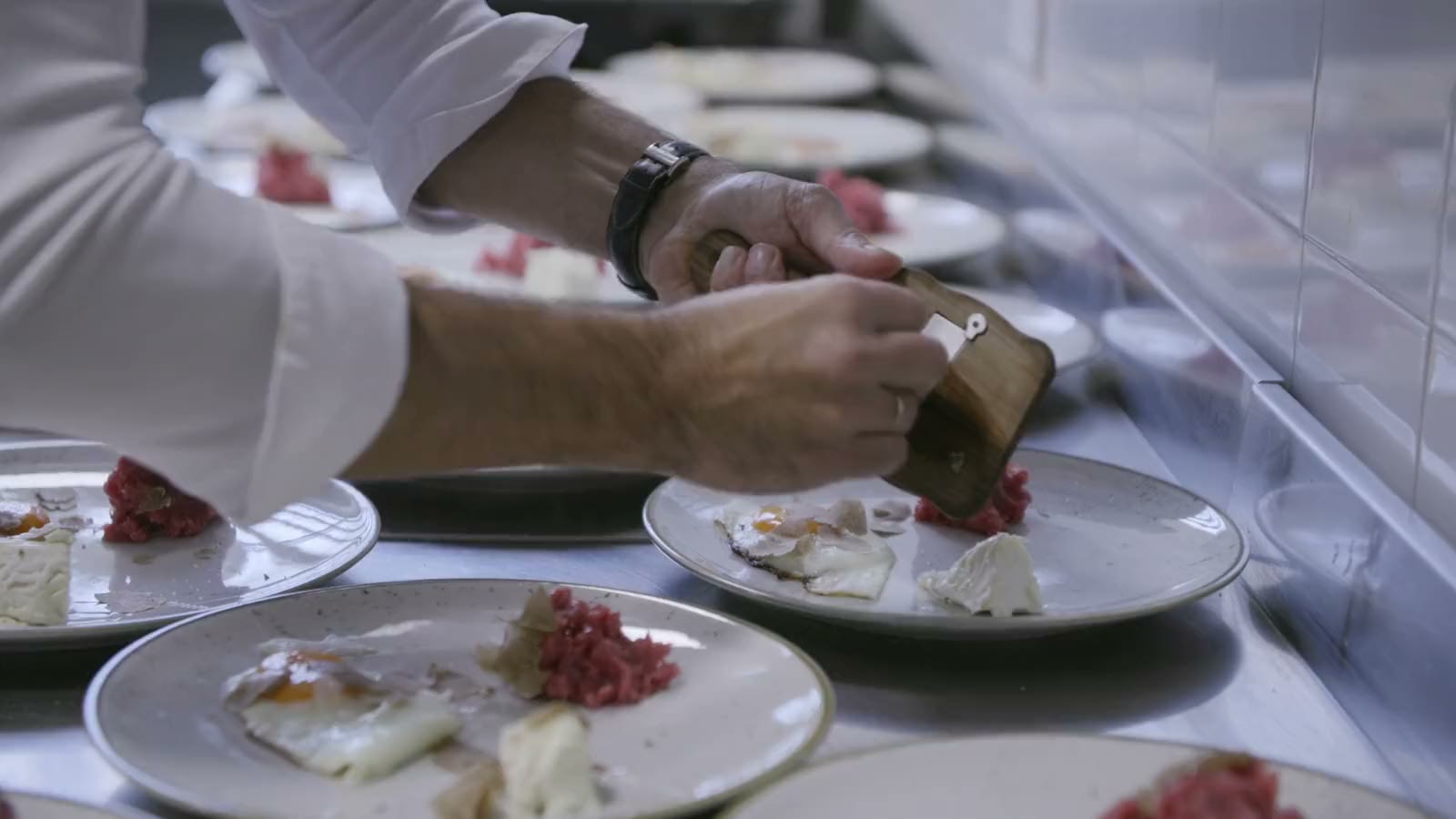 A chef’s hands finishing a row of plates
