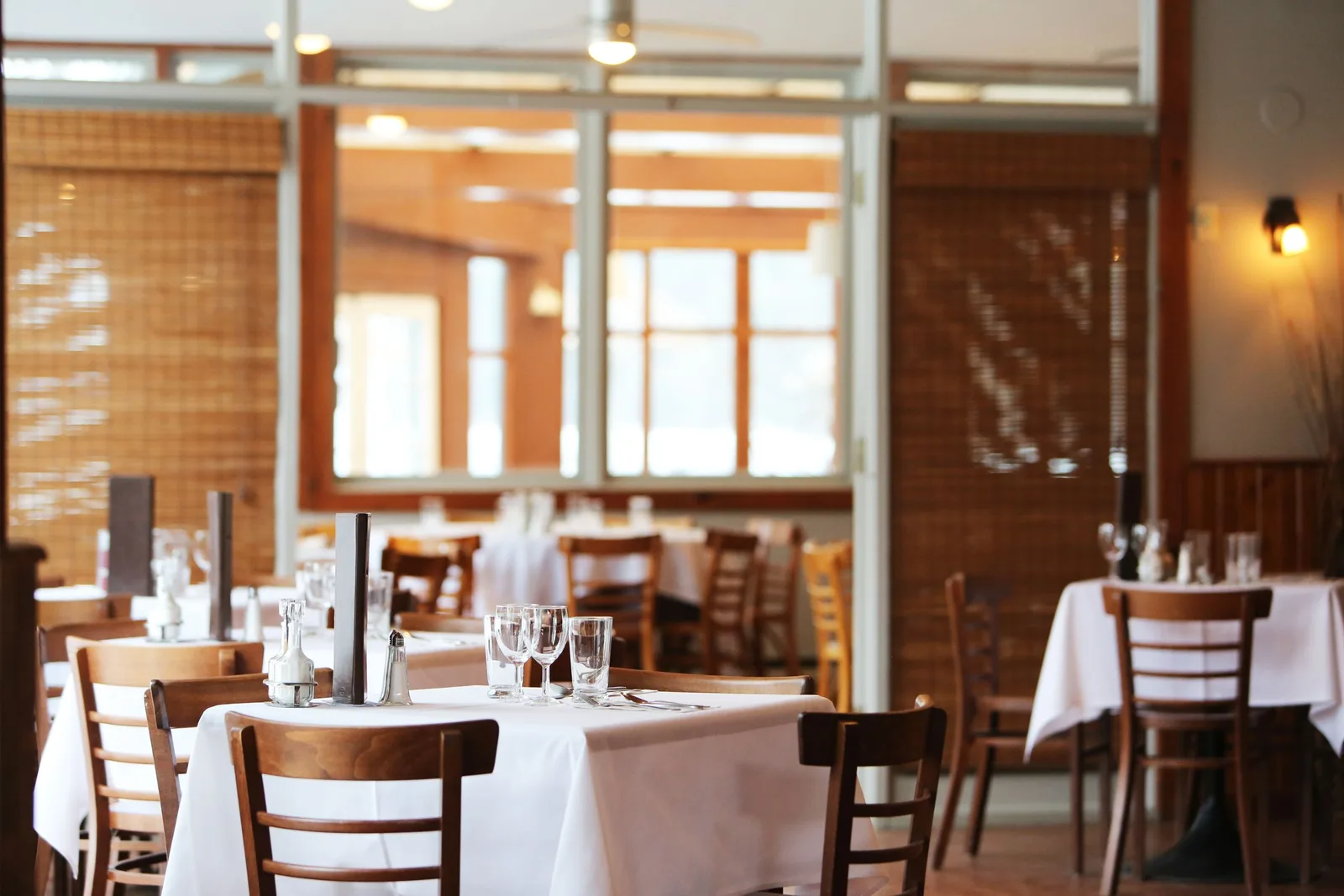 Tables with white cloths and wooden chairs in a bright dining room