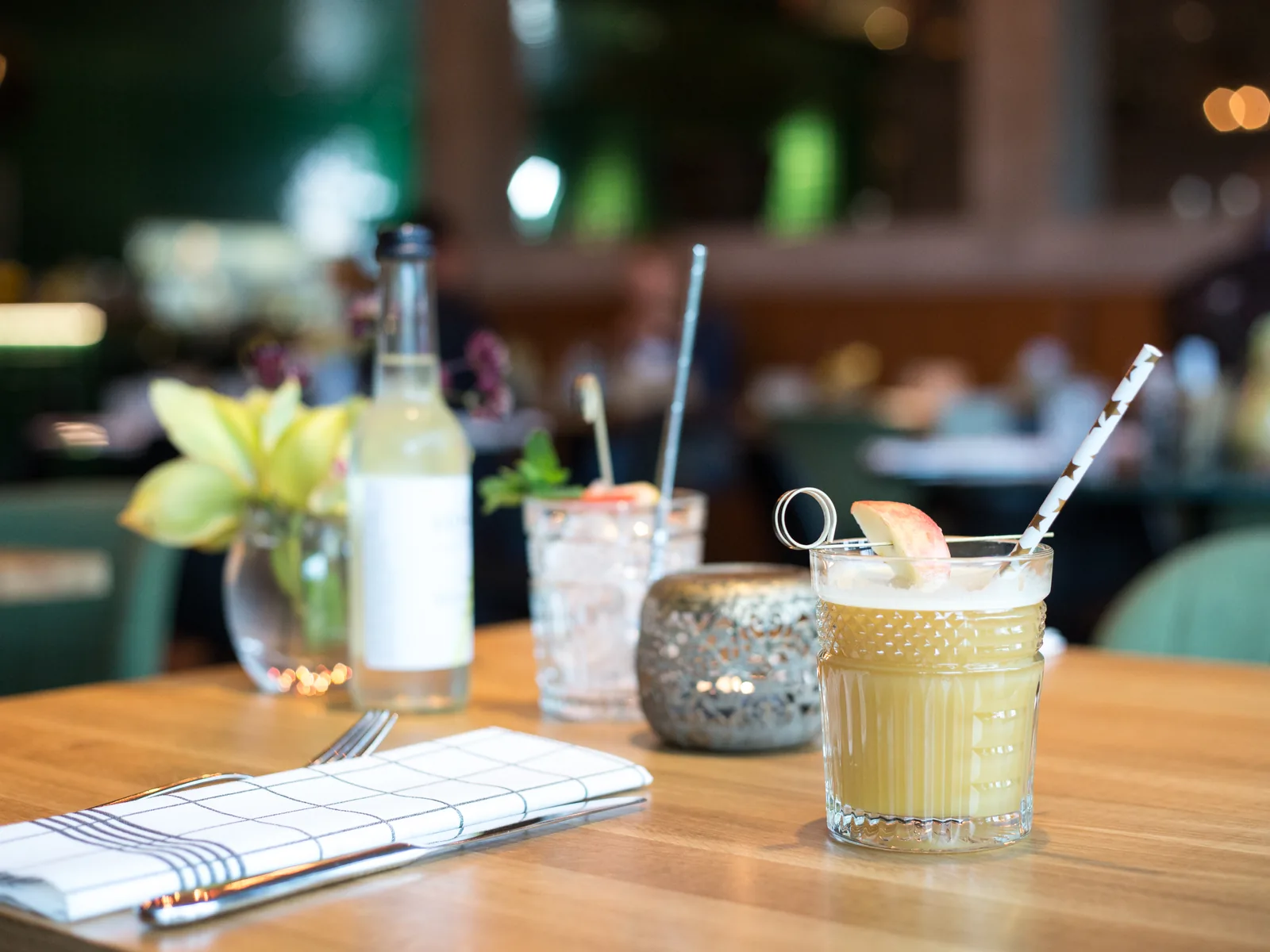 Cocktails and a bottle of water on a restaurant table, a folded napkin beside them