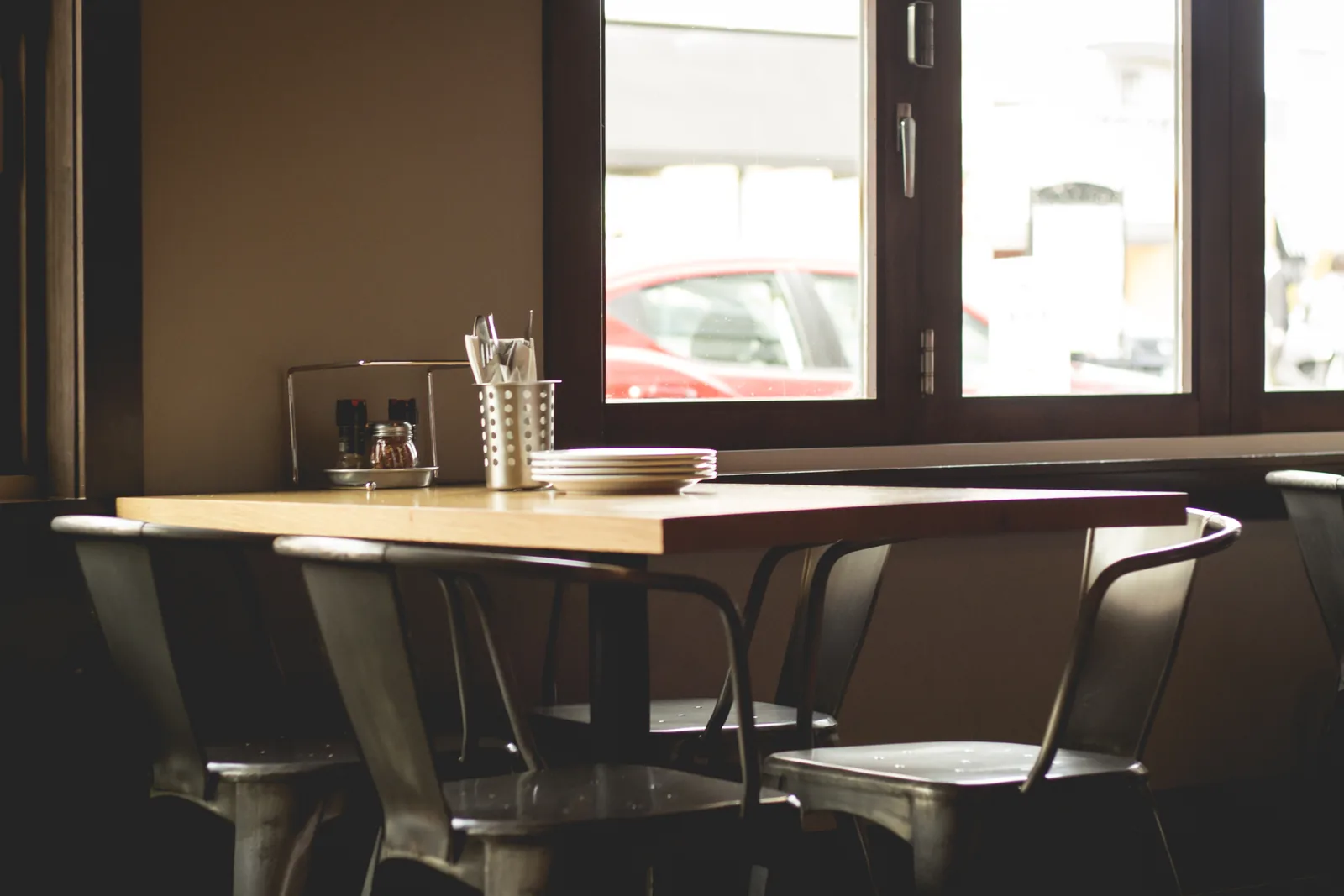 Empty wooden tables and metal chairs beside a window