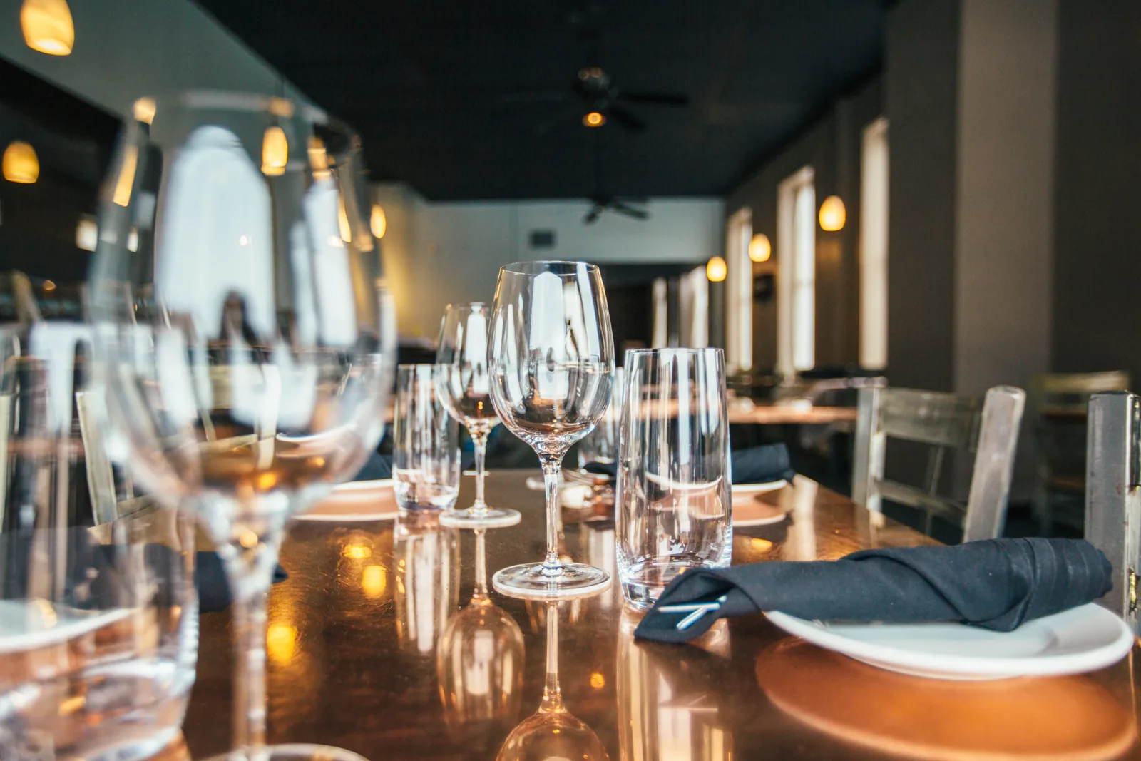 Wine glasses and folded napkins on a long table in a dining room